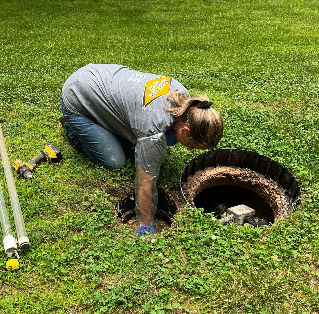 A State Line Septic technician checking an opened septic tank access