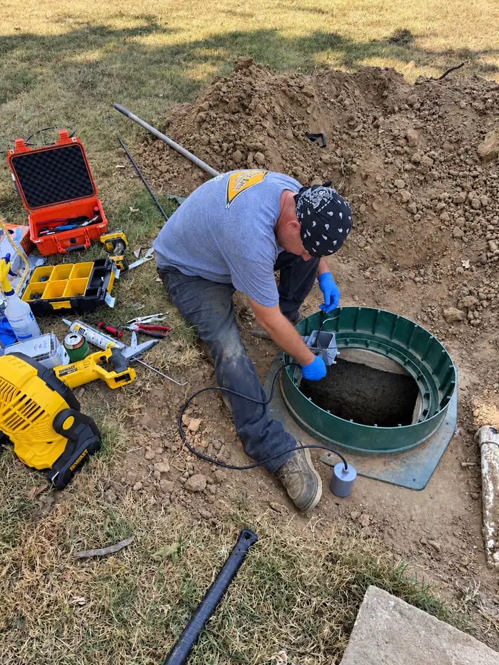 A State Line Septic technician installing a riser and alarm on a septic tank